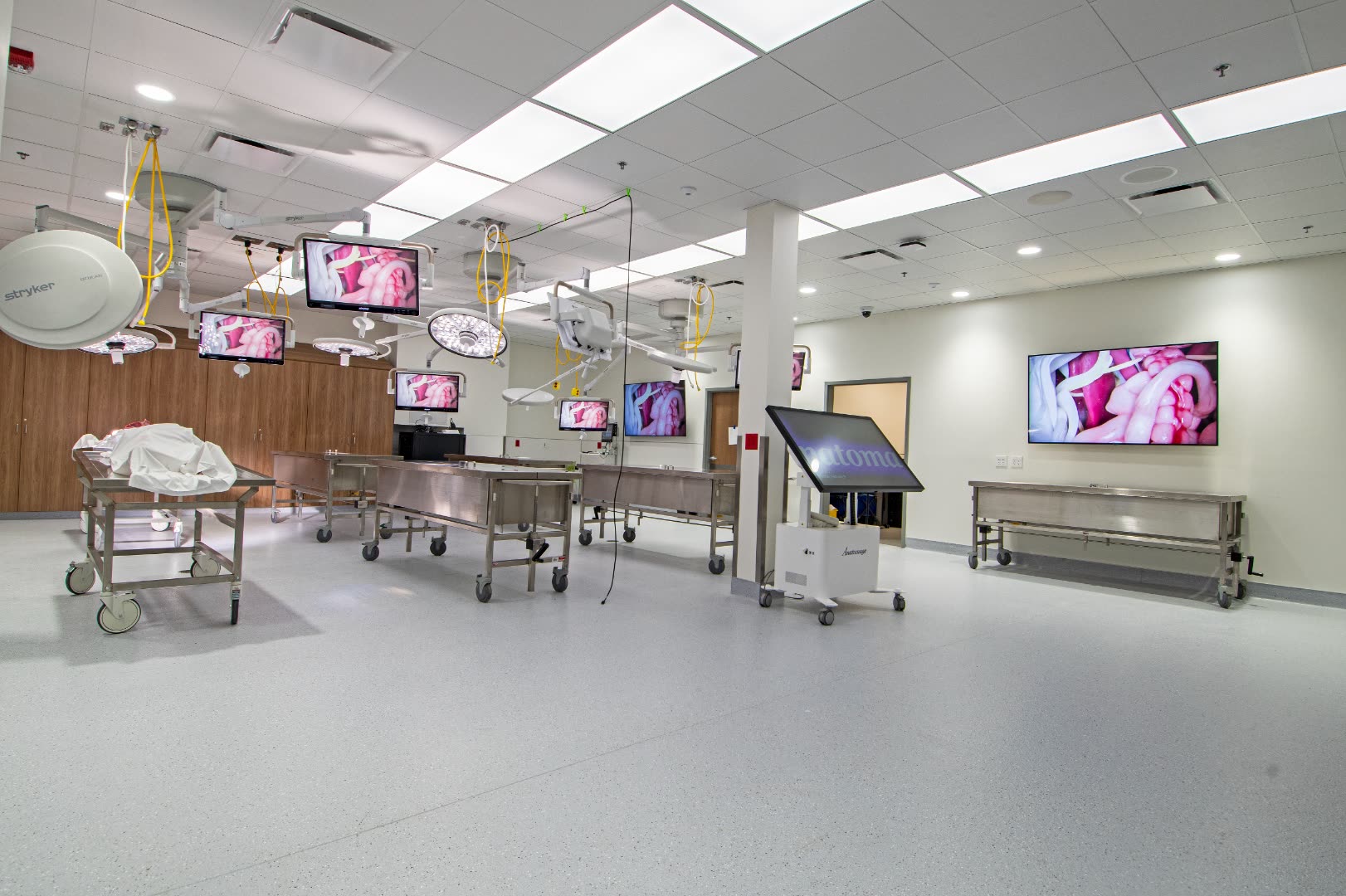 Simulated operating room with overhead displays showing surgical footage