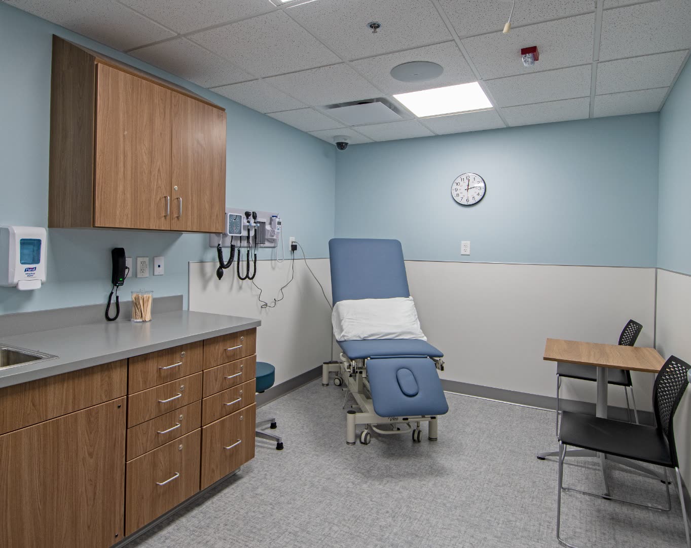 OSCE examination room with blue exam table, sink, and clock
