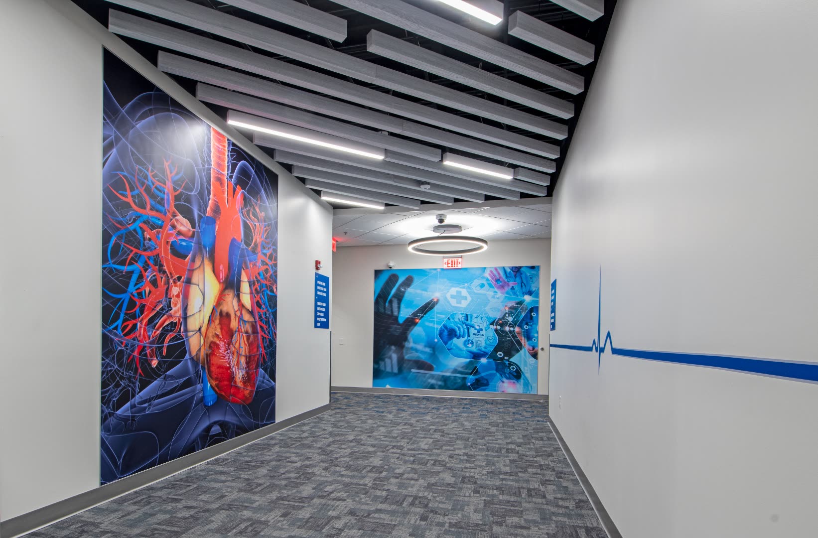 Hallway with anatomical heart mural, EKG line graphic, and tech wall art